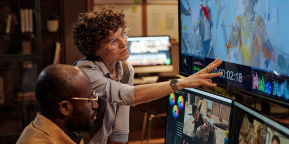 Project manager pointing at big display and giving instructions to colorist during their work at office